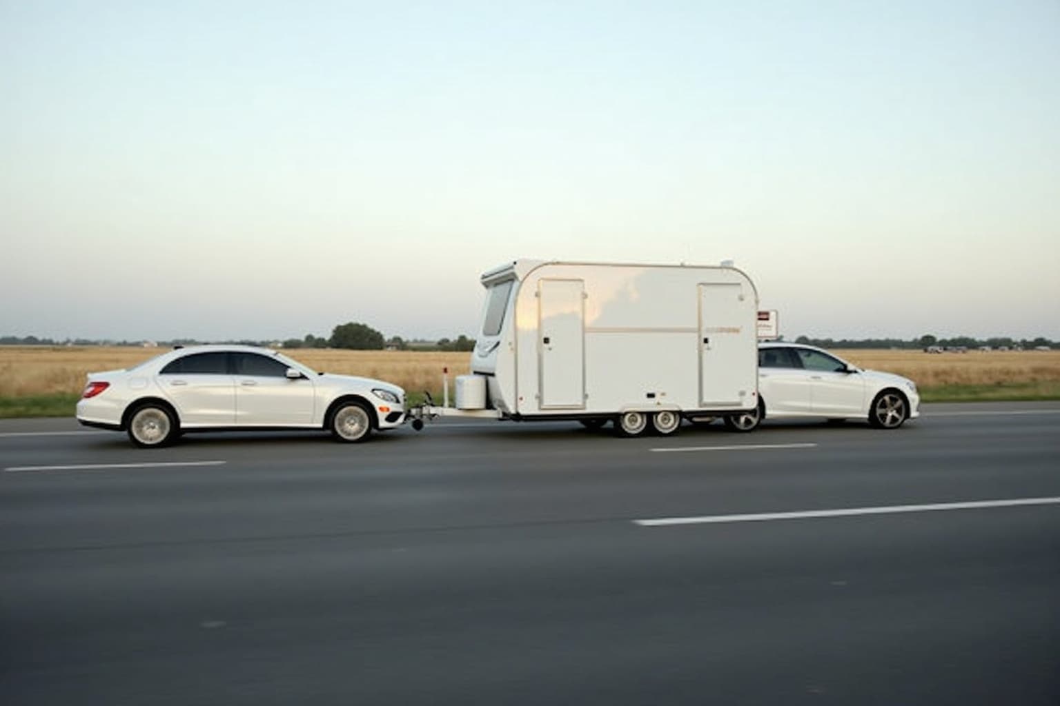 Fahrer am Steuer mit Wohnwagen-Gespann auf einer Landstraße