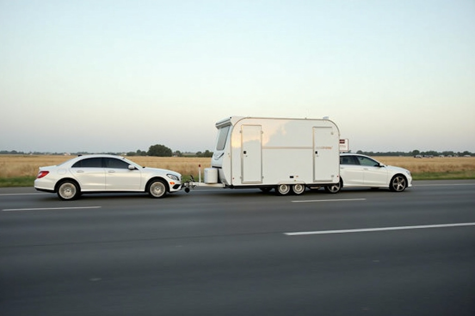 Fahrer am Steuer mit Wohnwagen-Gespann auf einer Landstraße